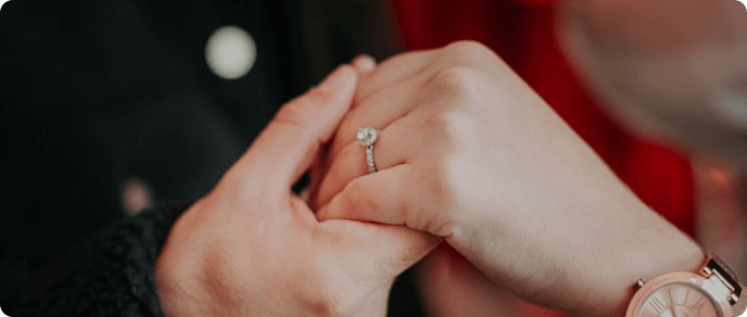 Couple holding hands with an engagement ring visible