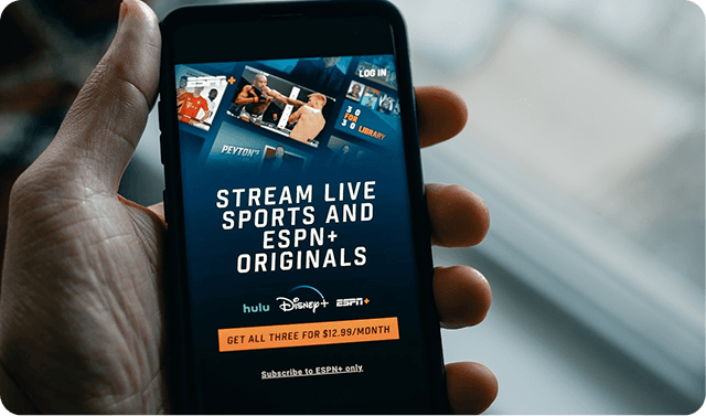 Hand holding a smartphone displaying a Hulu, Disney+, and ESPN+ streaming bundle offer