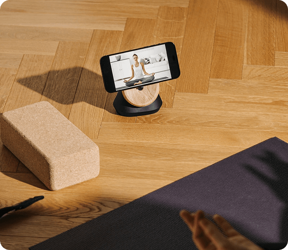 Smartphone on a stand next to a yoga block and mat
