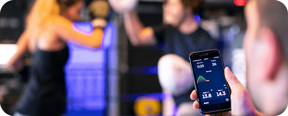 People exercising in a gym with a smartphone showing a fitness app