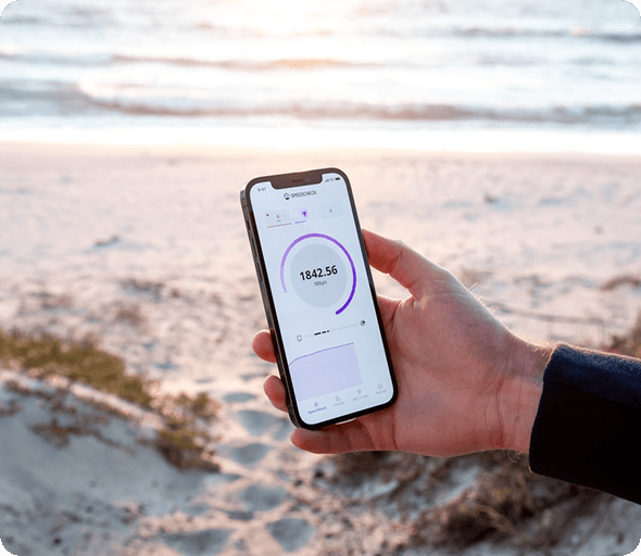 Hand holding a smartphone with a mood tracking app at the beach