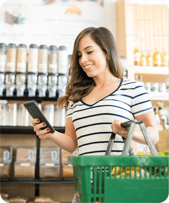 Shopper checking her phone while holding a grocery basket