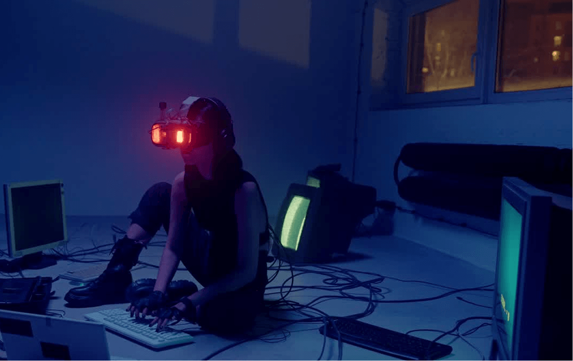 Person using a VR headset among computers in a dark tech workspace