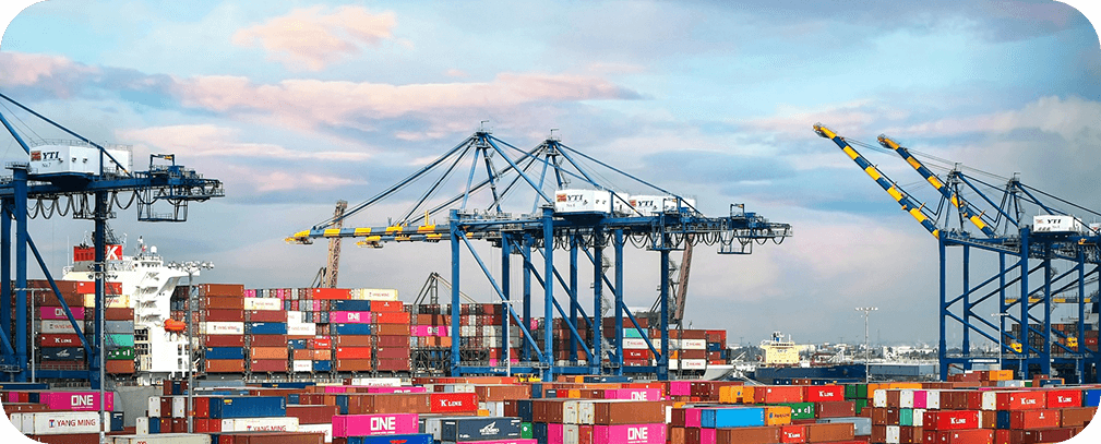 Container port with cranes and shipping containers at dusk