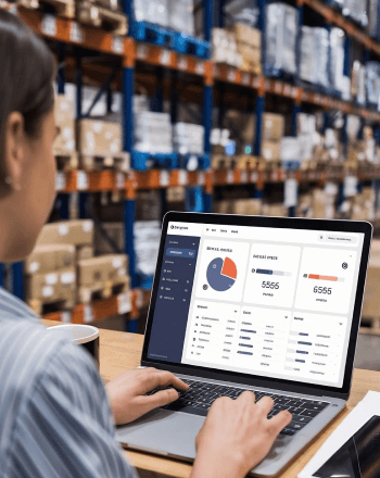Dispatcher reviewing a logistics dashboard on a laptop in a warehouse