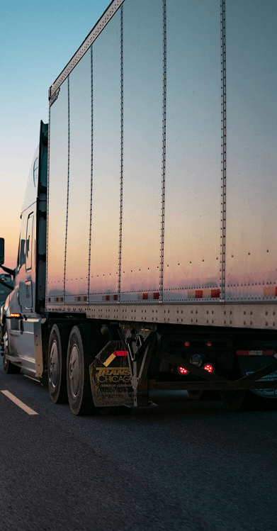 Semi-truck driving on a highway at dusk