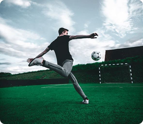 Soccer player kicking a ball on an outdoor pitch