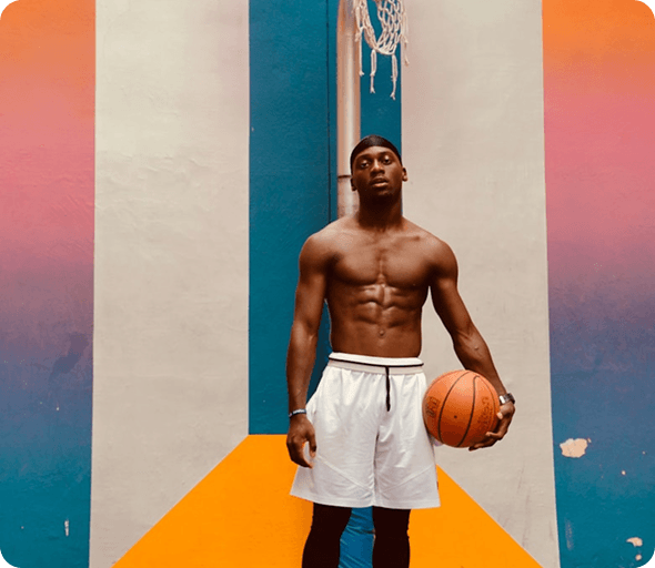 Basketball player holding a ball in front of a colorful court wall