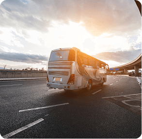 Modern transit vehicle moving through a city at sunset