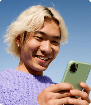 Person smiling while using a smartphone outdoors