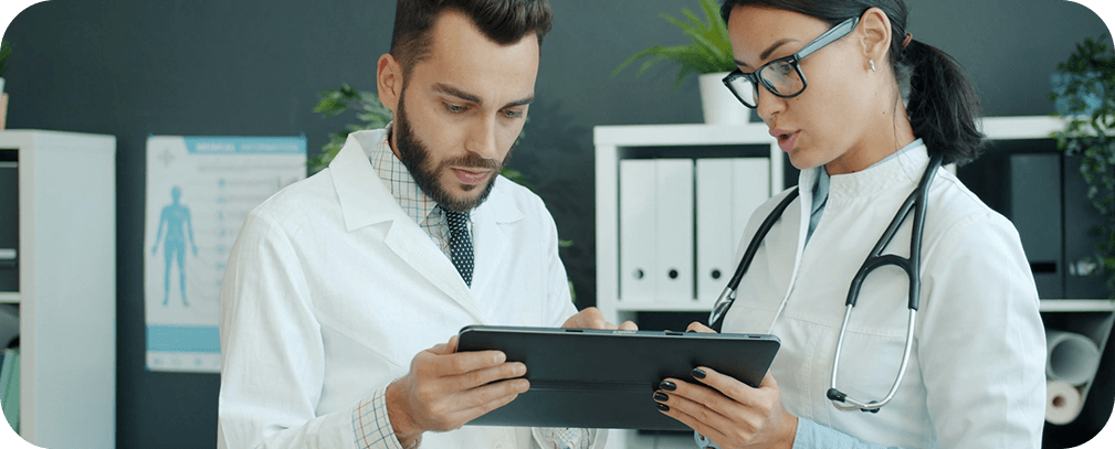Two healthcare professionals reviewing patient data together on a tablet
