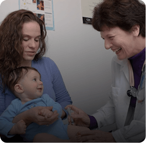 Pediatrician smiling with a mother and infant during a checkup