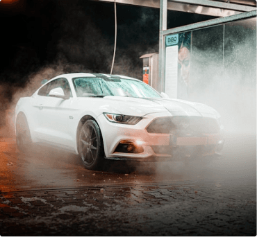 White sports car being washed in a spray bay
