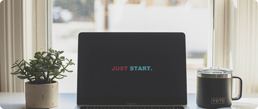 Laptop on a desk displaying the words Just Start