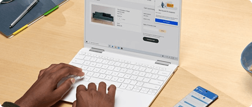 Hands typing on a laptop with a smartphone nearby