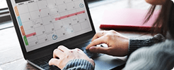 Hands using a laptop with a calendar scheduling interface