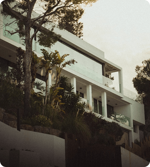 Modern multi-level villa with glass balconies surrounded by palm trees