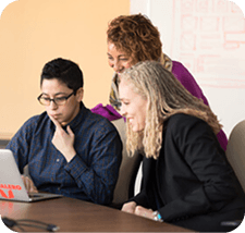 Team members collaborating around a laptop during a travel app planning session