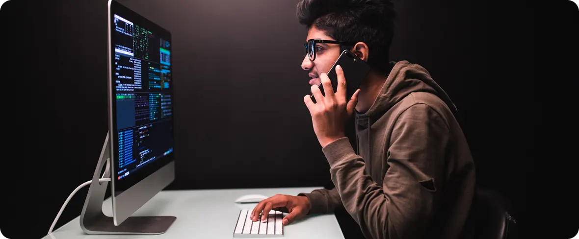 Cybersecurity specialist on a call while reviewing code and security dashboards