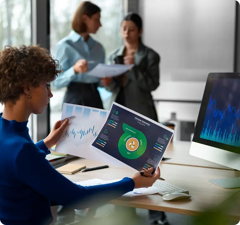 Analyst reviewing circular economy charts while colleagues discuss reports