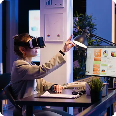 Woman using a VR headset at a desk with analytics on the screen