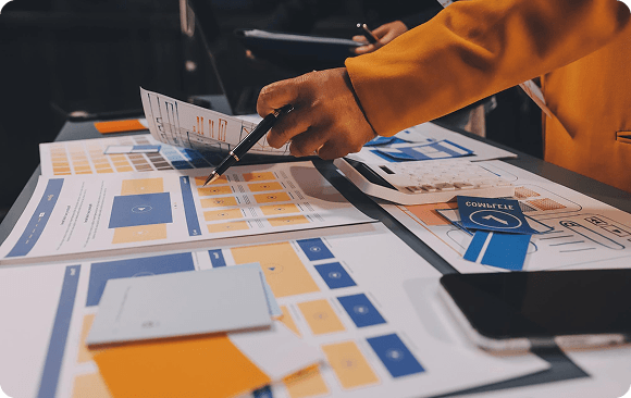 Hands reviewing printed brand mockups and design materials on a desk