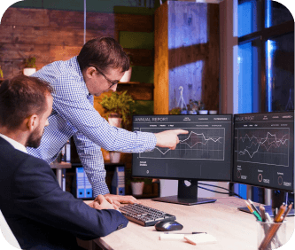 Two colleagues reviewing analytics on dual monitors at night